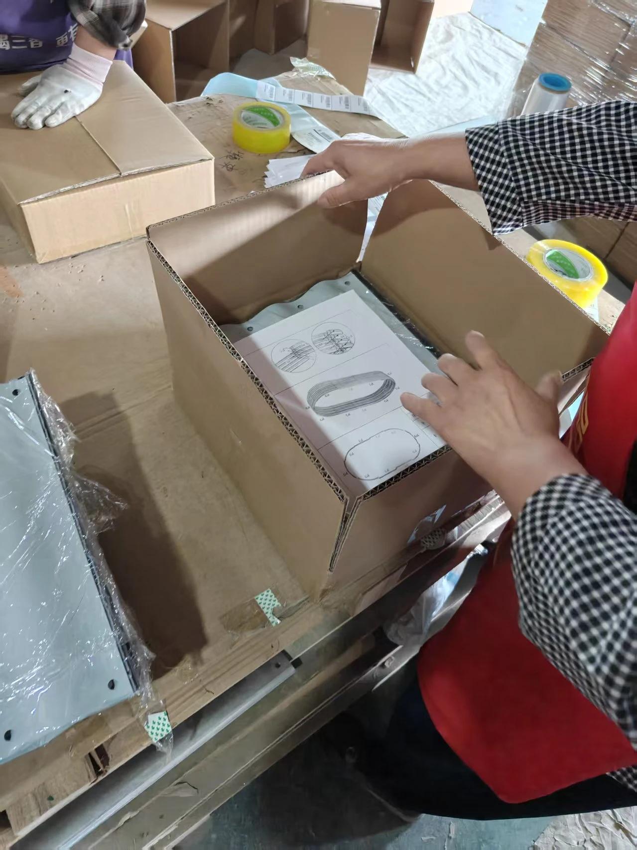 Raised Garden Bed Flat-Pack Packaging Workers packing galvanized steel raised garden bed parts into flat-pack cartons